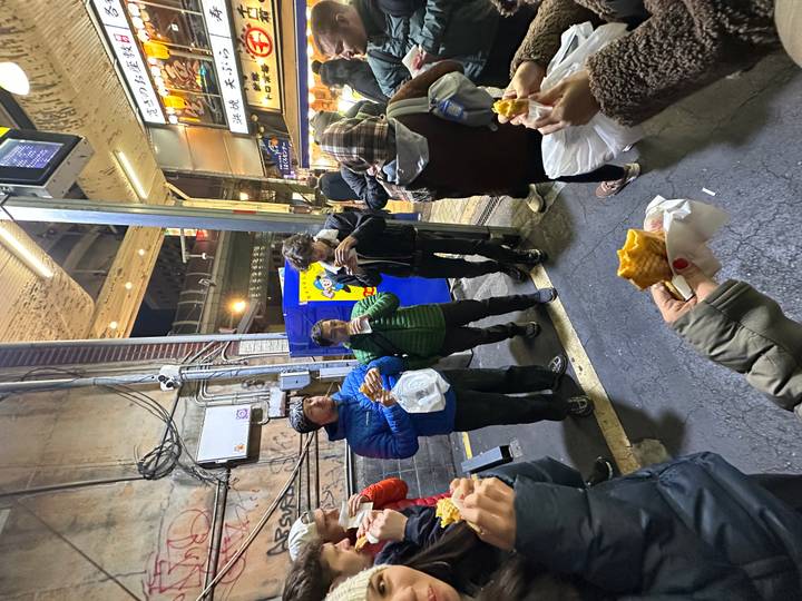 Des gens mangent des collations près d'un vendeur de rue.