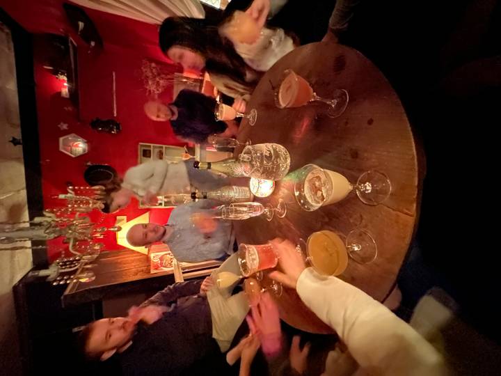 Des gens assis autour d'une table avec des boissons dans une pièce faiblement éclairée.