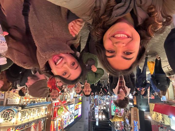 Un groupe de personnes souriantes dans une rue animée la nuit.