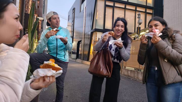 Groupe de personnes mangeant des pâtisseries dans la rue.