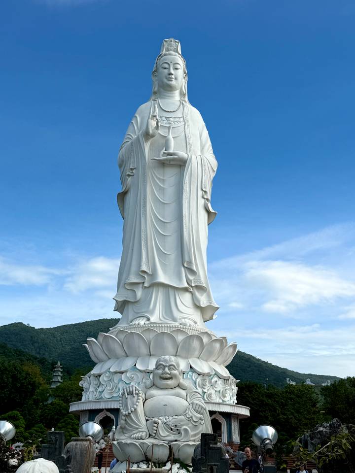 Gran estatua blanca de una deidad contra un cielo azul.