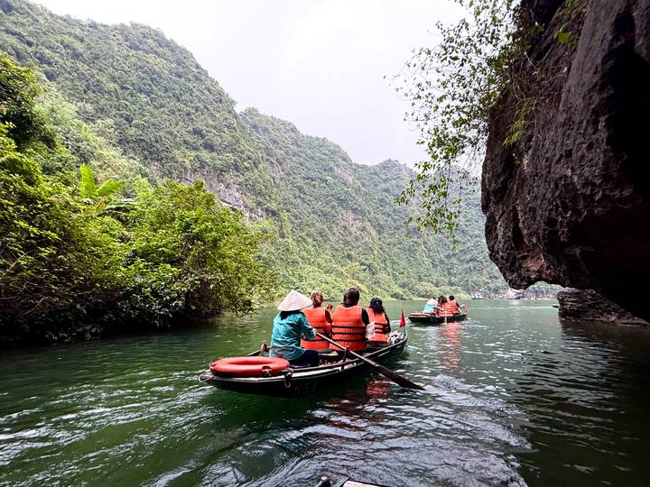 Turistas remando en un río rodeado de acantilados de piedra caliza.