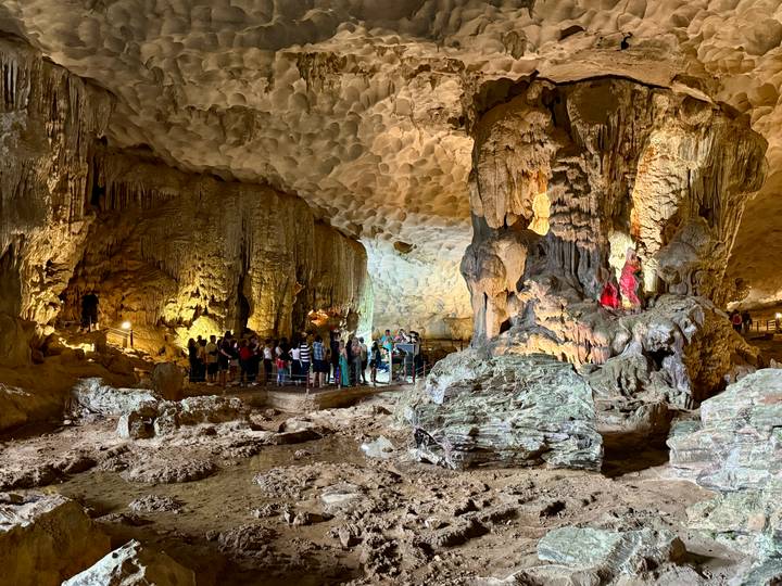 Turistas dentro de una gran cueva iluminada.
