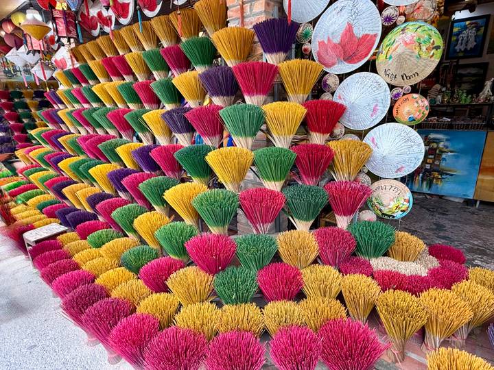 Varillas de incienso coloridas y sombreros tradicionales vietnamitas en exhibición.