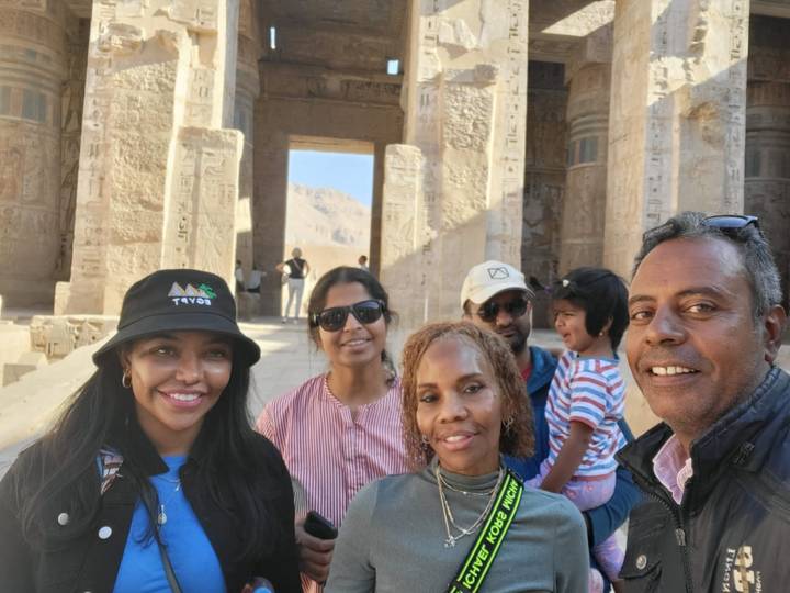 Gruppe von Touristen vor antiken Säulen mit Hieroglyphen.