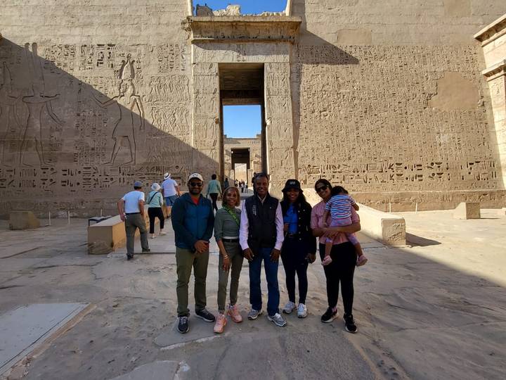 Gruppe, die vor einem antiken Tempel mit Hieroglyphen steht.
