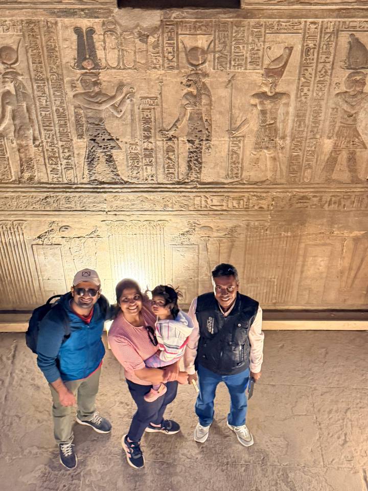 Familie posiert in einem Tempel mit beleuchteten Hieroglyphen.