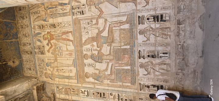 Person, die detaillierte Wandschnitzereien und Hieroglyphen betrachtet.