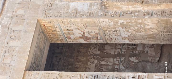 Person, die in der Nähe einer antiken Wand mit Gemälden steht.