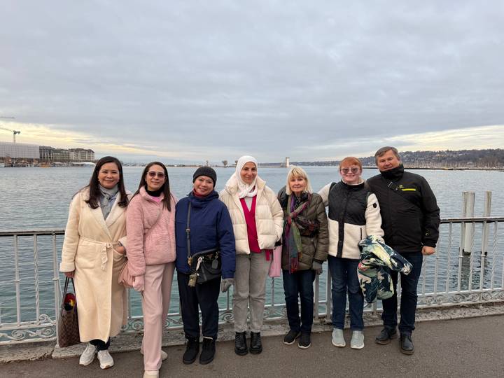 Groupe de touristes posant près d'un lac avec un ciel nuageux.