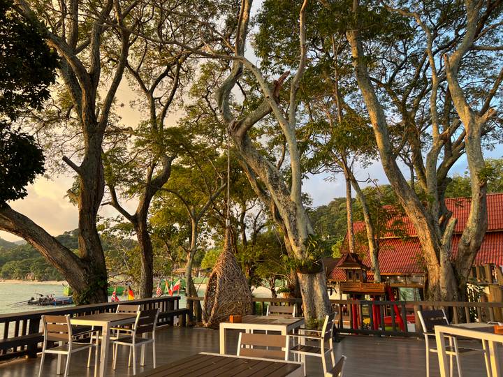 Una terraza con asientos en un exuberante jardín junto al mar.