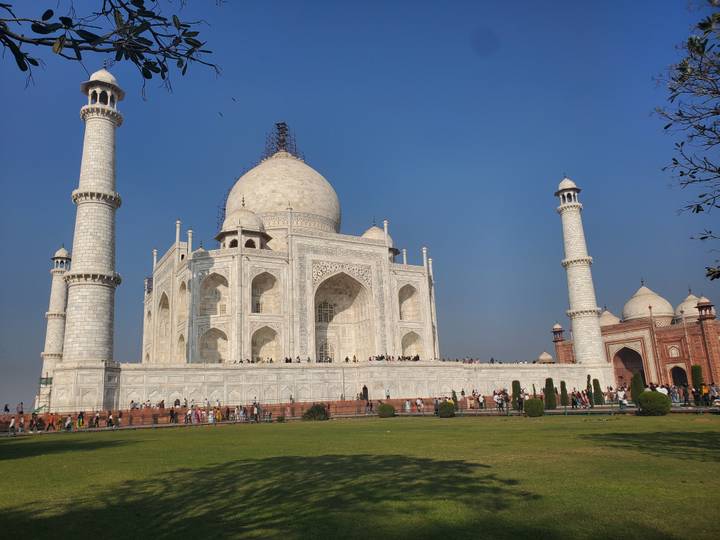 Das ikonische Taj Mahal unter einem klaren blauen Himmel mit Besuchern im Garten.