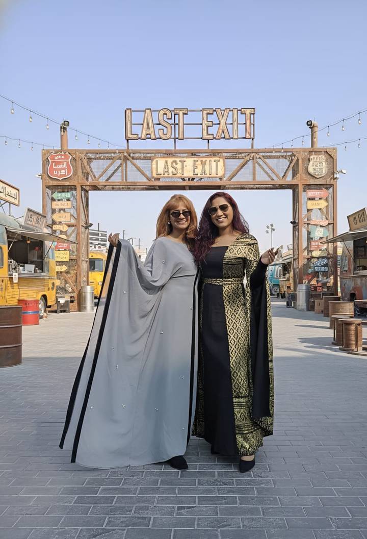 Zwei Frauen in traditionellen Kleidern auf einem Marktplatz im Freien.