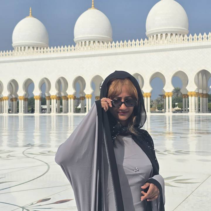 Frau in traditioneller Kleidung vor einem weißen Marmorgebäude.