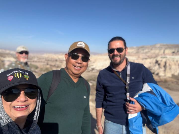 Grupo de amigos sonriendo con paisaje rocoso de fondo.