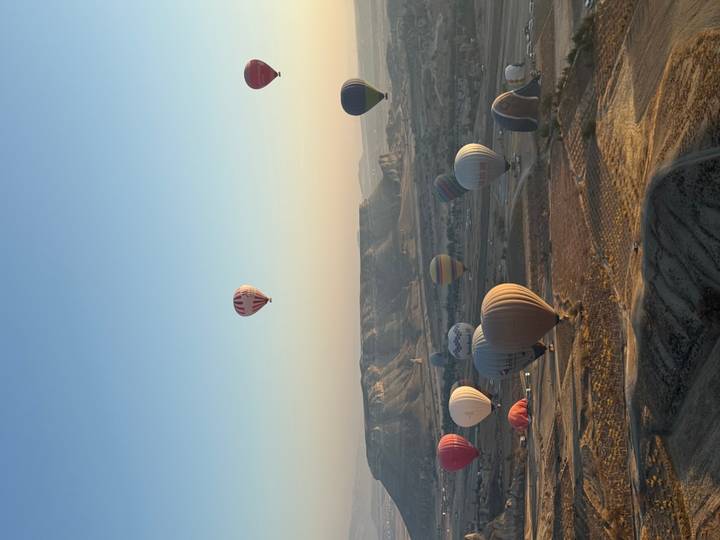 Globos aerostáticos sobre un paisaje escarpado al amanecer.