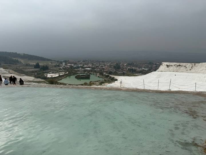 Piscinas termales con terrazas de travertino y una vista distante de una ciudad.