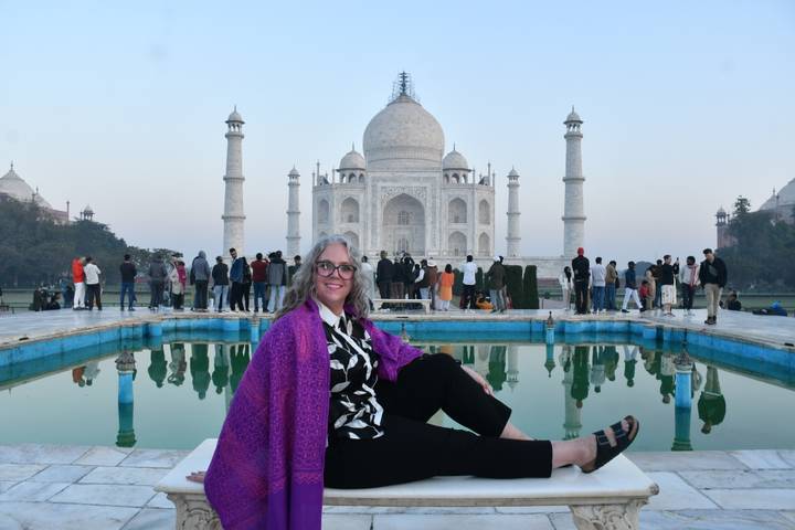Individuo sentado frente al Taj Mahal con una piscina reflectante.