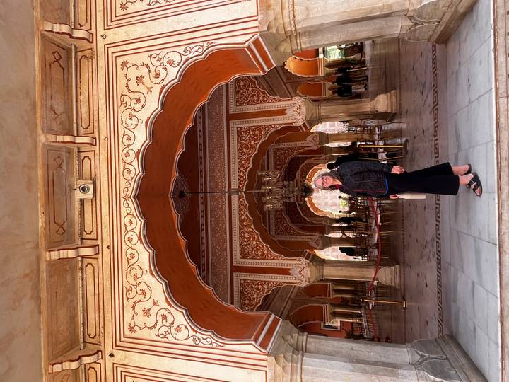 Persona parada dentro de un interior ornamentalmente decorado con arcos.