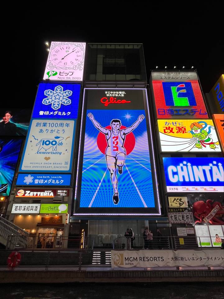 Panneaux publicitaires vivement éclairés dans un environnement urbain la nuit.
