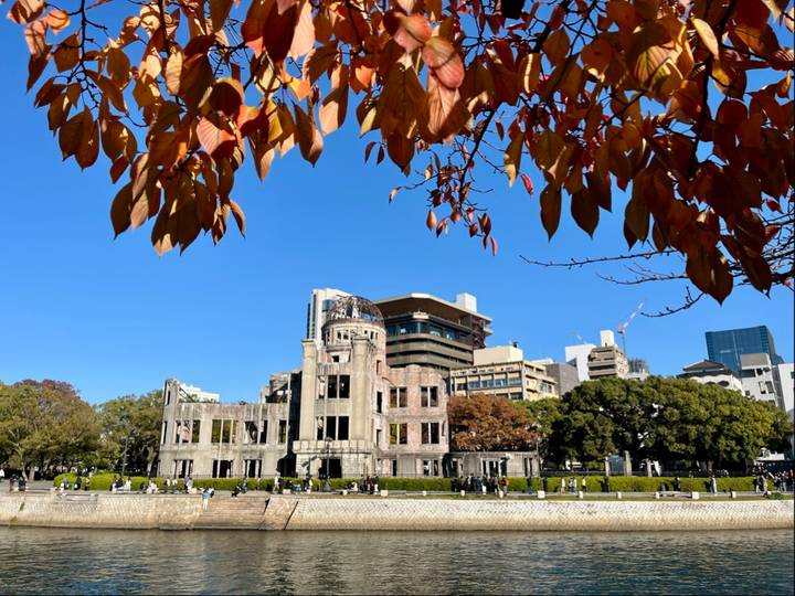 Bâtiment historique avec un toit en dôme et des feuilles d'automne encadrant la scène.