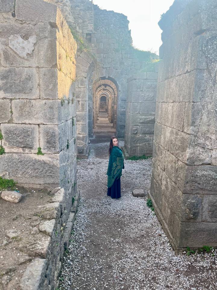 Una persona de pie en un corredor de ruinas antiguas.