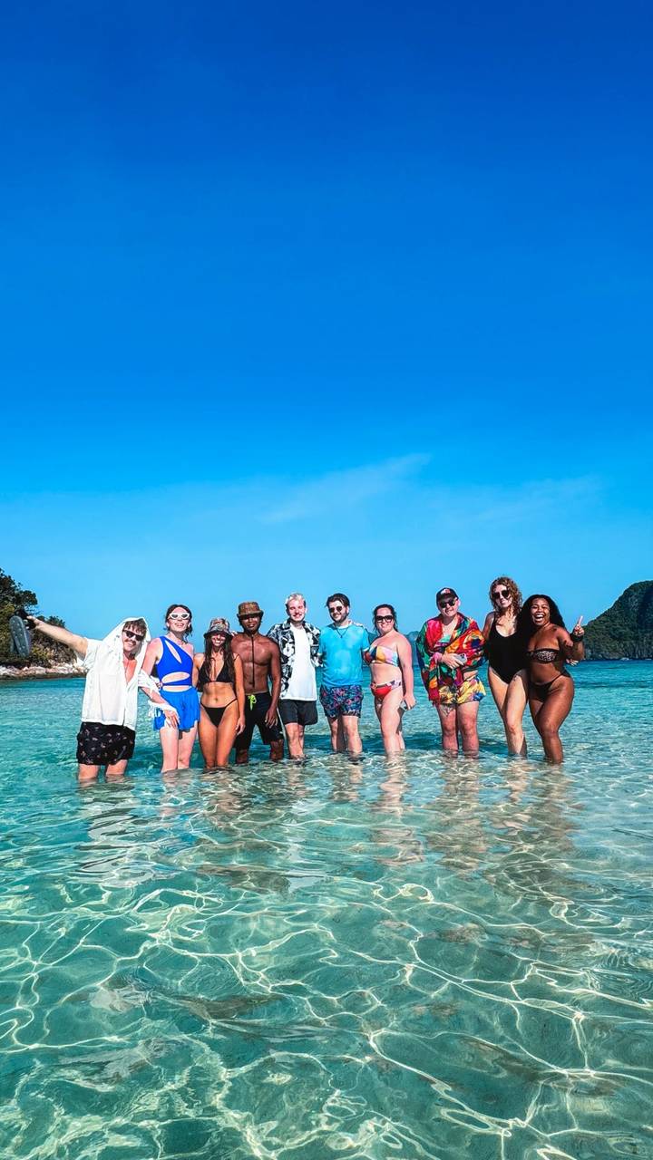 Gruppe von Menschen, die in flachem Meerwasser stehen, mit sichtbaren entfernten Inseln.