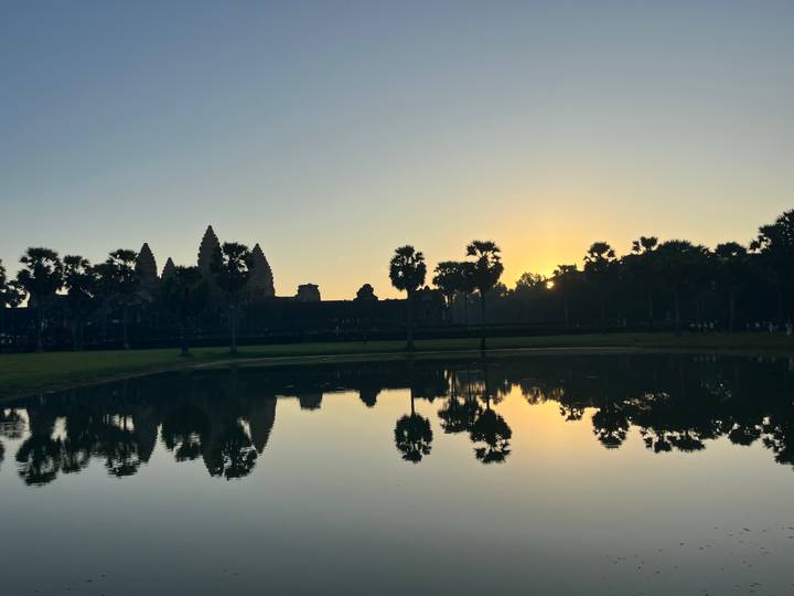 Silhouette von Angkor Wat bei Sonnenaufgang mit Spiegelungen im Wasser.