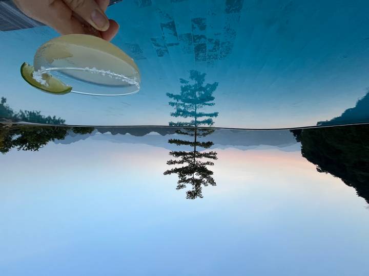 Infinity-Pool mit Cocktail mit Bergblick bei Sonnenuntergang.