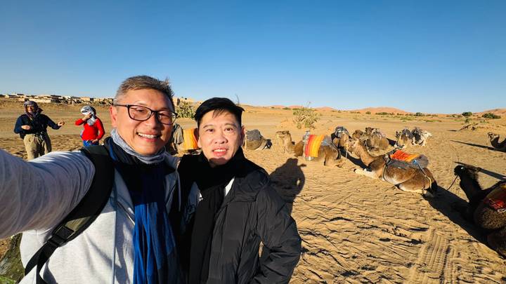 Dos personas con camellos en un desierto.