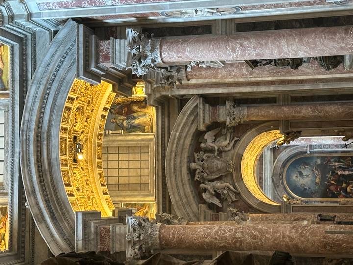 Interior de una iglesia histórica con decoraciones ornamentadas y pinturas.