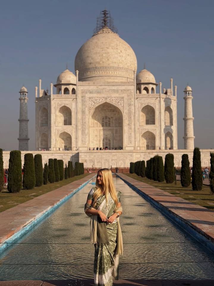 Taj Mahal met een vrouw die ervoor poseert.