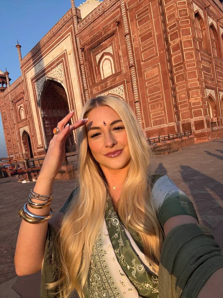 Persoon die een selfie neemt voor een rood decoratief gebouw.