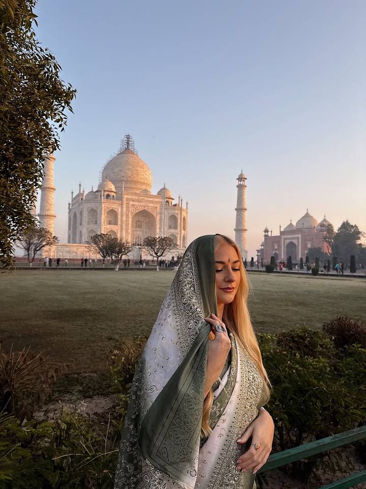 Vrouw in traditionele kledij met de Taj Mahal op de achtergrond.