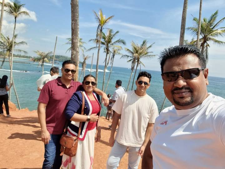 Menschen posieren bei Palmen und dem Ozean