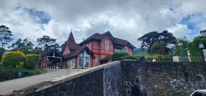 Landhaus mit roter Backsteinfassade, umgeben von Hügeln