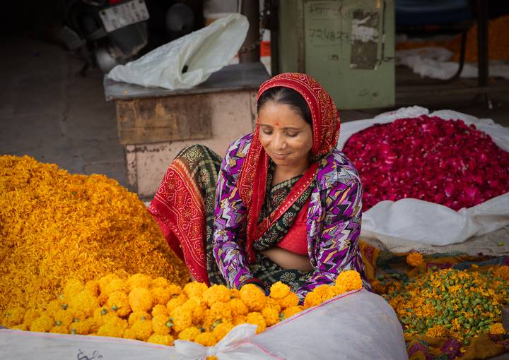 Femme assise parmi des fleurs de souci éclatantes dans un marché.
