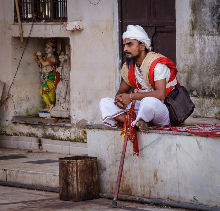 Homme en vêtements traditionnels assis près de l'entrée d'un bâtiment.