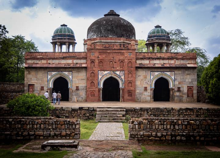 Architecture ancienne avec des personnes entrant par des portes voûtées.