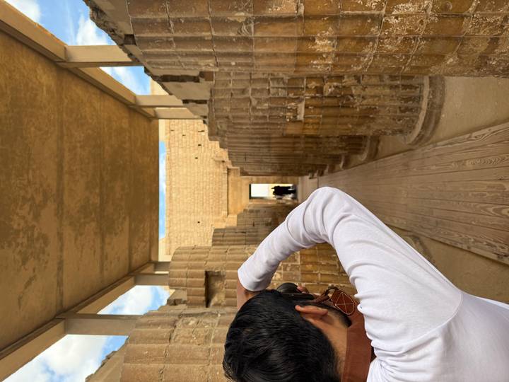 Persoon met camera fotografeert oude stenen zuilen.