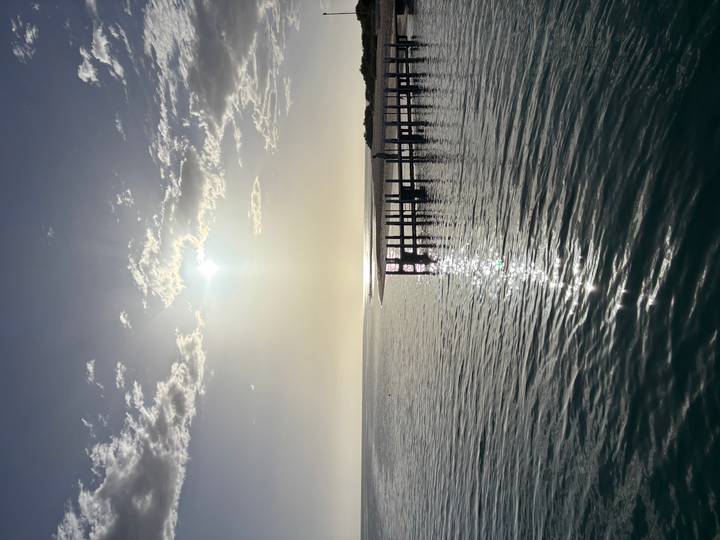 Uitzicht op de zee met een steiger en ondergaande zon.