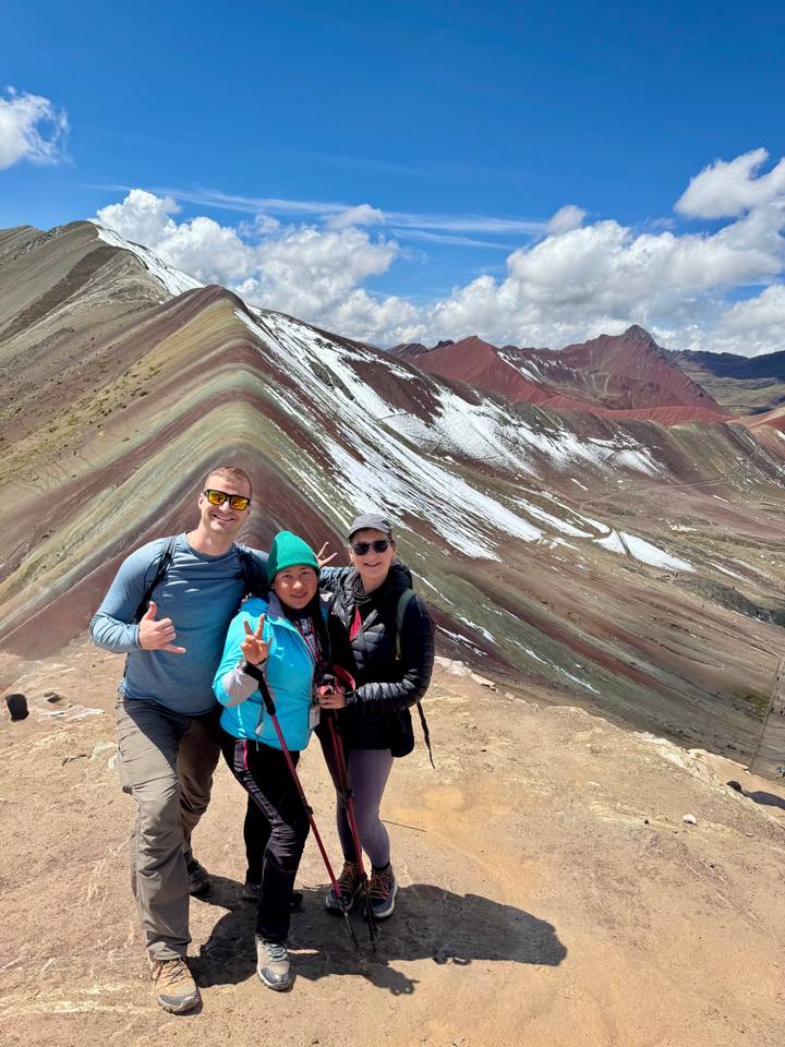 Smiling group of hikers at Rainbow Mountain with striped formations.