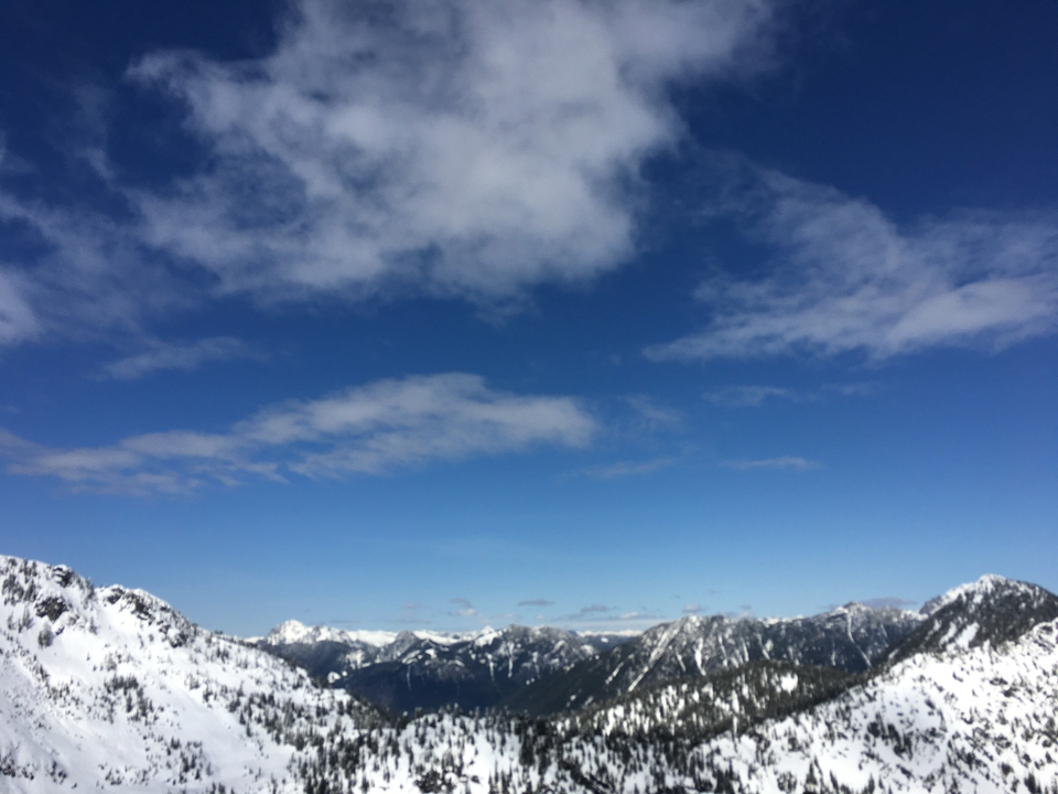 Vue large d'une chaîne de montagnes enneigées sous un ciel bleu.