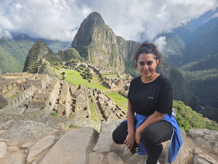 Woman sitting with Machu Picchu in the background.