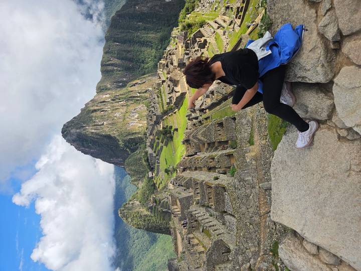 Person pointing at Machu Picchu ruins.