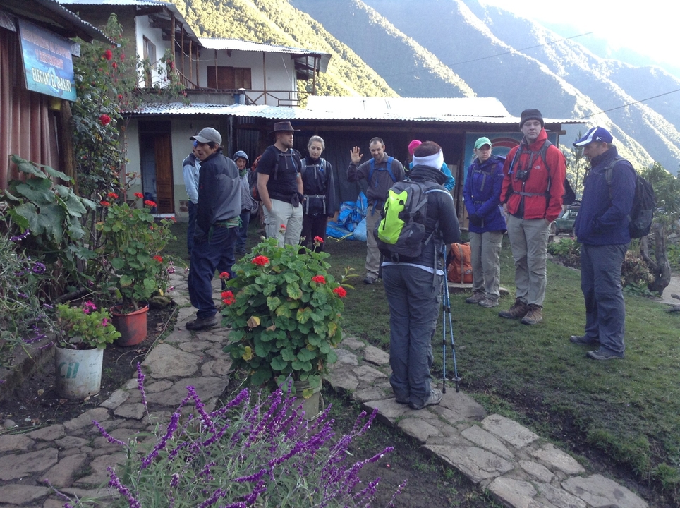 Un groupe de randonneurs s'est rassemblé devant un bâtiment entouré de fleurs.