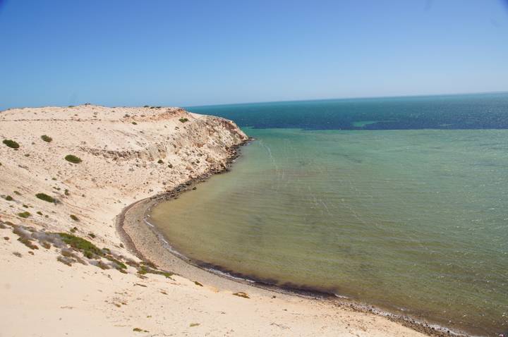 Coastline with sandy cliffs and turquoise water.