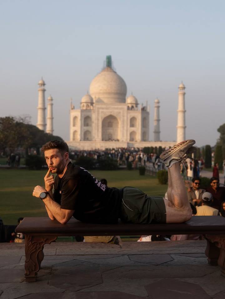 Touriste posant de manière ludique devant le Taj Mahal.