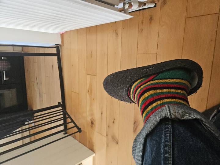 Primer plano de calzado con calcetines coloridos sobre un suelo de madera.