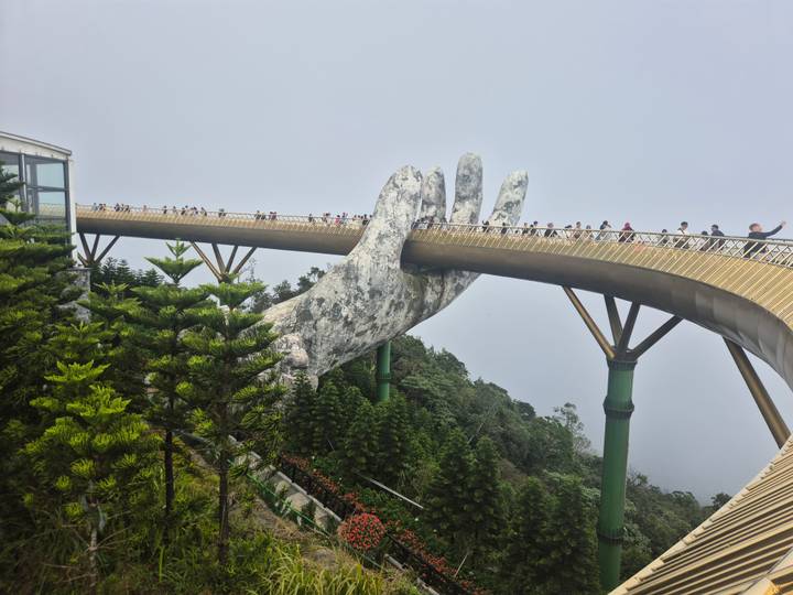 Puente Dorado con manos gigantes en Vietnam con turistas caminando.